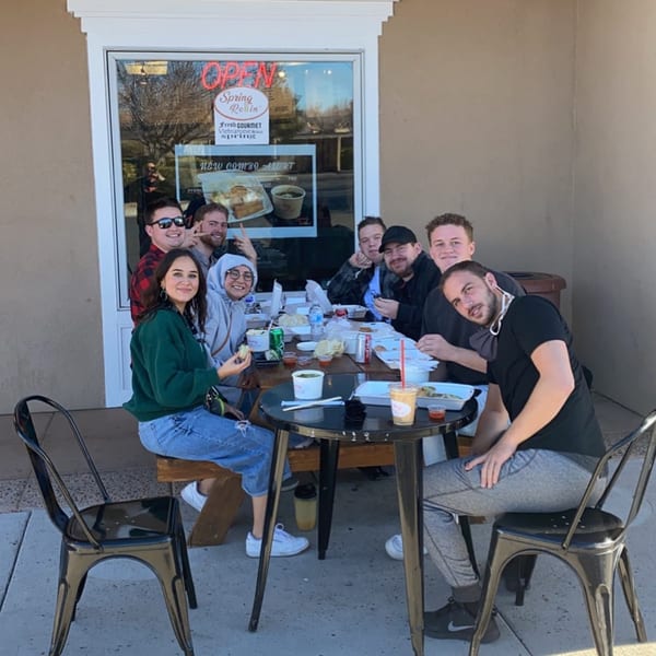 A group of young people enjoying Vietnamese food and drinks at an outdoor table at Spring Rollin.