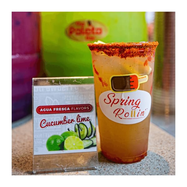 A Spring Rollin' drink with a chili-lime rim next to an "Agua Fresca Flavors" sign.