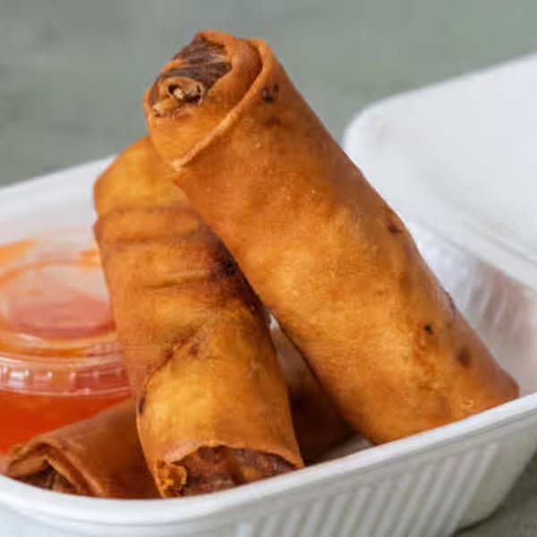 Three crispy Vietnamese spring rolls in a white takeout container with a side of sweet chili sauce.