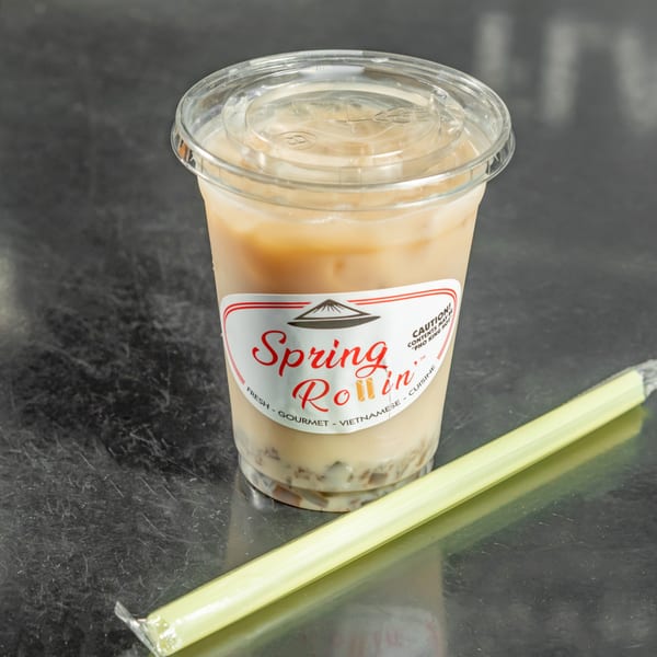 Spring Rollin's Vietnamese iced coffee with a straw on a dark, reflective surface.