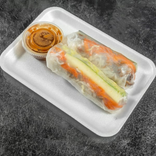 Two fresh Spring Rollin' Vietnamese spring rolls with peanut sauce in a white takeout container.