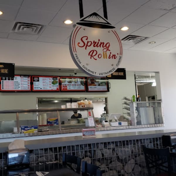 The Spring Rollin' sign hangs above the counter with menus and a person working in the background.