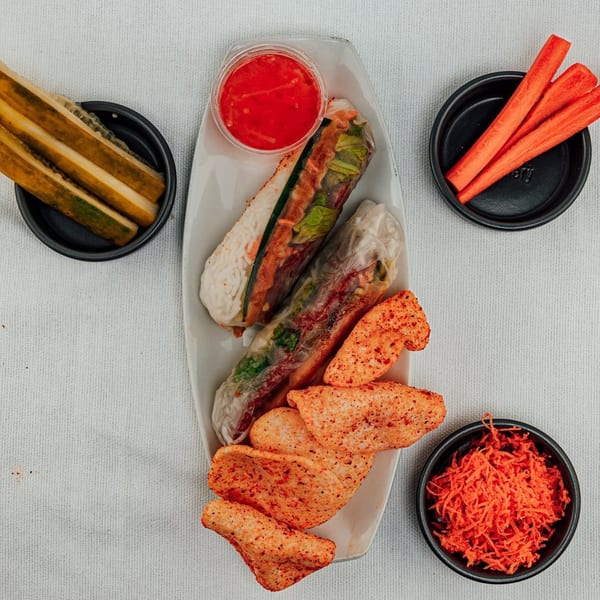 Overhead view of Spring Rollin's Vietnamese spring rolls, spicy chips, pickles, carrots, and shredded carrots.