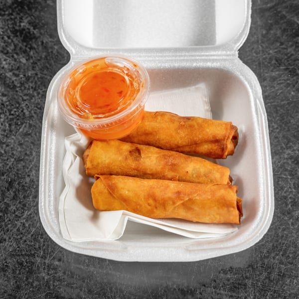 Three golden-brown Spring Rollin' Vietnamese spring rolls and a container of dipping sauce in a takeout box.
